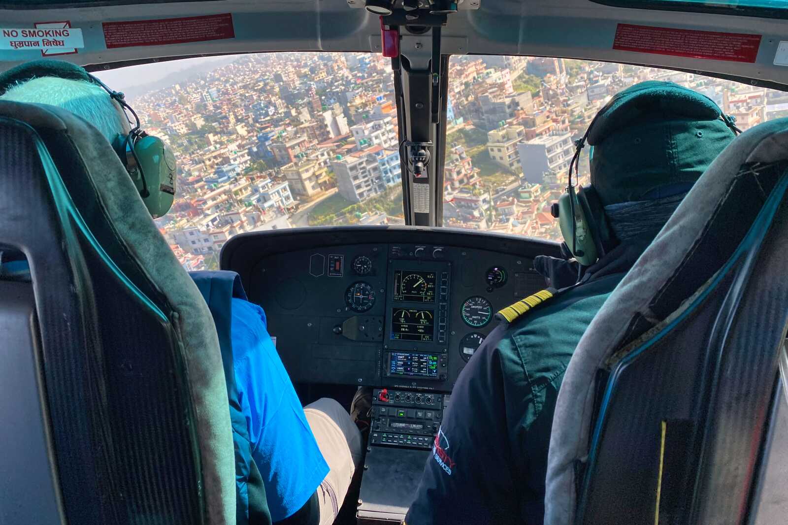 A pilot and passenger flying a helicopter over Kathmandu, Nepal.