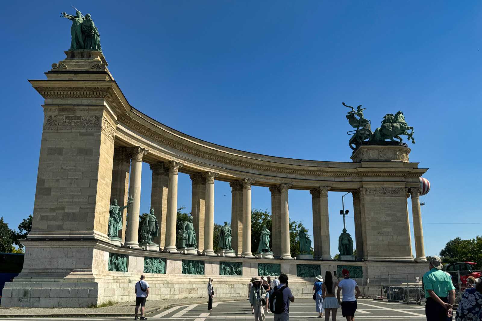 People in Heroes Square admiring the statues in Budapest, Hungary.