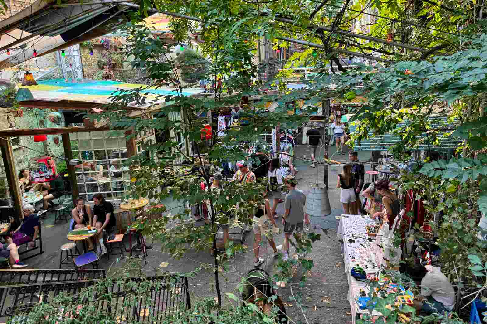 People enjoying a drink in the green courtyard in the Szimpla Kert ruin bar in Budapest, Hungary.