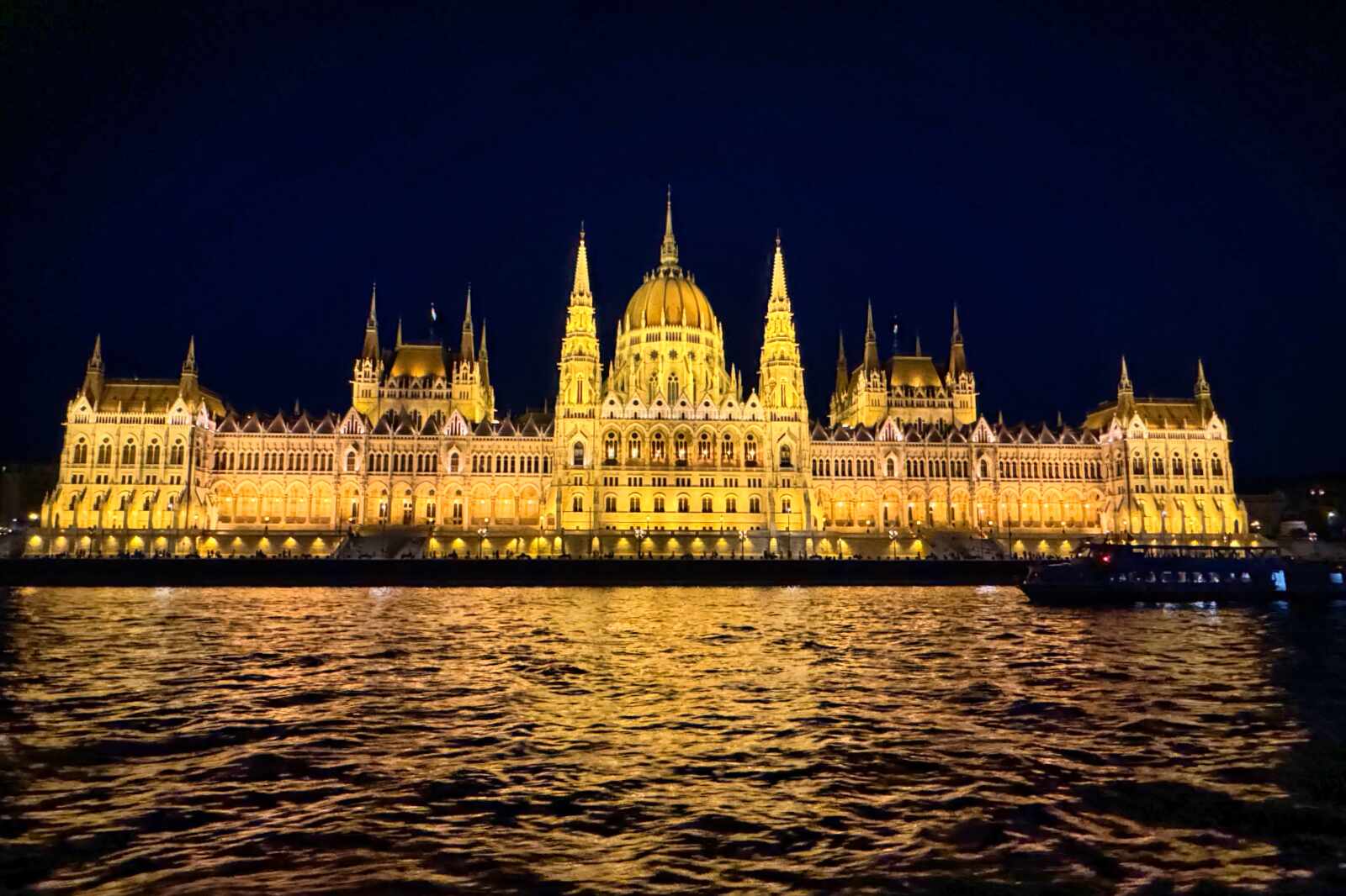 A view from a boat cruise of the Hungarian Parliament at night.