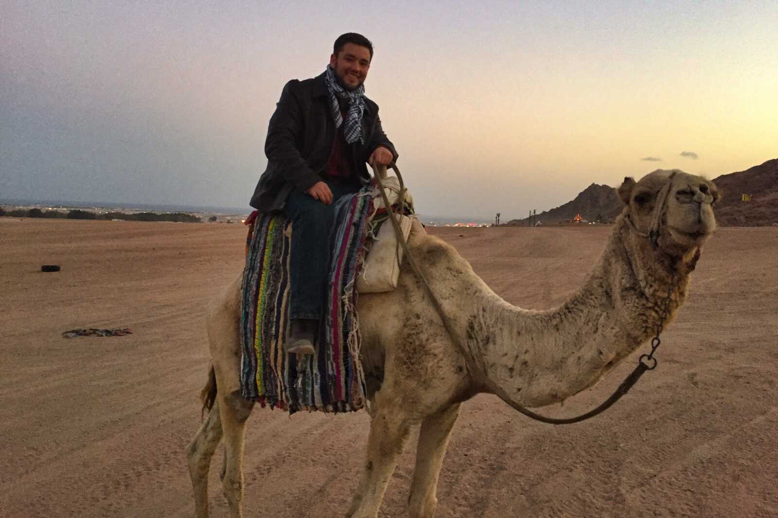 A man smiles and rides a camel in the Sinai desert in Egypt.