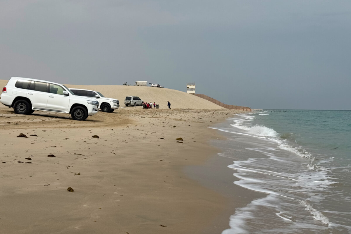 Cars are parked at the shoreline of the Persian Gulf.